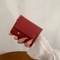 Petit portefeuille rouge foncé en cuir avec clous dorés tenu à la main - Rouge