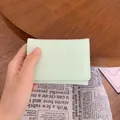 Portafoglio corto verde menta con orsetto e fiocco goffrati tenuto in mano - Verde