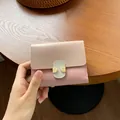 Short women's bifold wallet in beige and pink faux leather with a green strap buckle - Pink