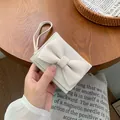 Mini portafoglio chic bianco crema con fiocco grande e cinturino su tavolo - Bianco Sporco