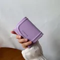 Petit portefeuille en cuir lavande avec logo Classic Star tenu à la main - Mauve Clair