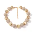 Detail van de kralenketting met beige harskralen en gouden getextureerde kralen - Melkwit