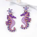 Macro shot of colorful rhinestone seahorse earrings with purple enamel flower studs - Purple Flower Seahorse Style / Purple