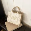 Dettaglio borsa tote color crema con motivo a farfalla e cinturino su panca in pelle - Grande / Bianco