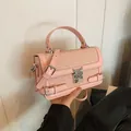 Roze minimalistische crossbodytas met geweven textuur en hartslot in de hand - Roze