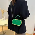 Petit sac carré vert vif avec bordure dorée et poignée torsadée porté par un modèle - Vert Émeraude