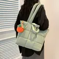 Quilted mint green tote bag with puffer texture and charm shown on a female model - Single Bag / Green