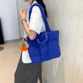 Sac fourre-tout matelassé bleu avec charm carotte, porté en bandoulière par un mannequin - Bleu