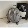 Detail of grey nylon backpack featuring elastic side pockets and shiny silver shoulder straps - Gray