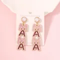 Detail of MAMA gold drop earrings with pink rhinestones and pearls on display - Pink M Red A
