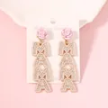 Macro detail of MAMA letter earrings with pink rose, pearls, and crystals on a card - Creamy White Flower Top
