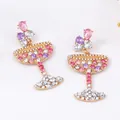 Detailopname van cocktailglas oorbellen met roze kristallen en gouden basis - Kleurrijke Steen Stijl