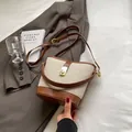 Bolso tipo cubo retro de lona y cuero marrón con hebilla dorada sobre una chaqueta - Marrón