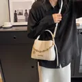 Detail der cremeweißen Falten-Beuteltasche mit Goldkette und Metall-Logo-Plakette - Gebrochenes Weiß