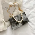 Artistic marble pattern crossbody bag with gold chain and large pearl handle detail - Black