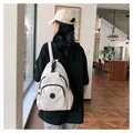 Detalle de una mini mochila casual blanco roto con bolsillo frontal y parche decorativo - Blanco