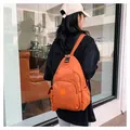 Foto en exterior de una mochila de nailon naranja vibrante usada como bolso bandolera - Naranja