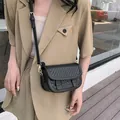 Elegante borsa a sella nera con trama a intreccio e fibbie in metallo dorato - Nero