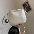 Minimalist beige textured bucket bag with sleek silver ball charm and long shoulder strap - White