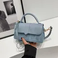 Detail van lichtblauwe crossbodytas met denimtextuur en gouden hardware accenten - Blauw Gesplitst Denim Textuur