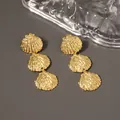 Three-tier gold shell drop earrings with textured metal finish on a grey surface - Three Layer Gold Scallop Earrings
