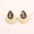Detail of drop-shaped grey crystal earrings with a hammered gold metal texture - Black