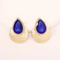 Close-up of teardrop earrings with dark blue stones and gold hammered texture - Blue