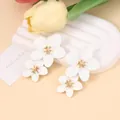 Macro detail of elegant double layered white flower earrings with golden floral stamens - White Earrings