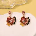 Detailed view of turkey-shaped drop earrings featuring red and yellow rhinestones - Red