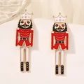 Elegant Nutcracker stud earrings in red and gold finish on a white display stand - Red