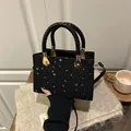 Bolso negro con tachuelas de estrellas plateadas, asa trenzada y detalles metálicos dorados - Negro