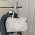 Minimalist cream white high capacity canvas tote bag with front pocket and fashion label - White