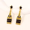Detail of champagne bottle drop earrings with black enamel star stud and bubbly text - Wheat