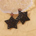 Bohemian black hollow star wooden drop earrings on a textured paper background - Black