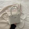 Elegante borsa a tracolla bianca lucida con logo fashion su un blazer beige di stile - Bianco