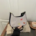 Grey suede crescent bag with colorful embroidered bows and black leather strap handle - Gray