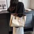 Detailed view of bicolor large tote bag with double handles on model in minimalist setting - Coffee