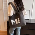 Minimalist dark grey canvas tote bag with M! print and wide shoulder straps on a model - Zipped with Inner Pocket / Black