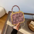 Pink marble texture box bag with gold metal frame and twisted handle on a table - Pink