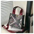 Detail of geometric woven tote bag with metallic twist lock and red carry handles - Black Small