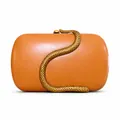 Macro view of the luxury snake-shaped gold clasp on an amber faux leather clutch - Orange