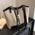 Chic beige canvas tote bag with black leather trim and elegant gold twist lock buckle - Black