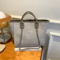 Grau-beige gewebte Beuteltasche mit braunen Ledergriffen und Metallkettenriemen - Khaki