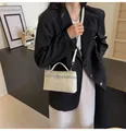 Dettaglio borsa crema effetto coccodrillo con finiture argento e doppia chiusura a zip - Bianco
