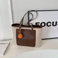 Minimalist canvas tote bag in off-white with dark brown leather pocket and orange charm - With Charm / Brown