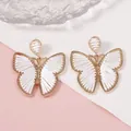 Pendientes de mariposa tejidos a mano con marcos dorados y detalles de hilo blanco - Blanco