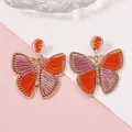 Pendientes de mariposa hechos a mano con hilo de seda naranja y violeta en marco dorado - Naranja