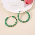 Detail of bohemian green clay bead hoop earrings with gold spacers on a stylist display - Verdant