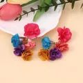 Detailansicht farbenfroher Stoffblumen-Ohrhänger auf elegantem Blumenhintergrund - bunt