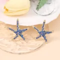 Close-up of starfish earrings with blue zircons on wavy glass for beach style - Gold Plated Blue Zirconia